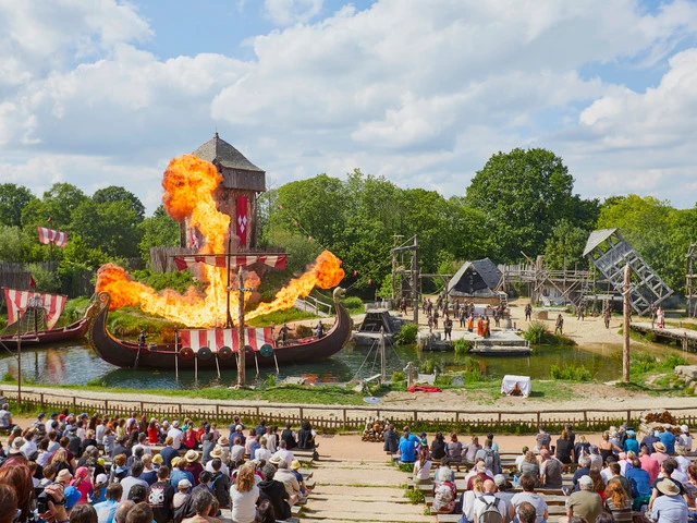 le bateau des viking en feu sur l'eau, au premier plan les gradins avec les spectateurs au Puy du Fou